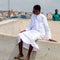 Unidentified Ghanaian man in white clothes sits on the fence in