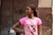 Unidentified Ghanaian woman in pink shirt with braids stands in