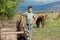 Unidentified happy kid playing at organic farm with horse and vineyard in Alazani valley with mountains