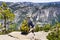 Unidentified hiker sitting on a rock and looking towards Yosemite Valley and Upper Yosemite Falls, Yosemite National Park,