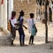 Unidentified local girls walk from behind with bags in the Etig