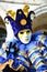 An unidentified man in blue and yellow fancy dress with mask, joker hat with rattles, blue ring and gloves during Venice Carnival