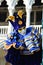 An unidentified man in blue and yellow fancy dress with mask, joker hat with rattles, blue ring and gloves during Venice Carnival