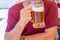 An unidentified man drinks out of a large glass mug of light beer on the background of a pub on a wooden table