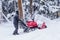 Unidentified man use his red snow removal machine to clear path