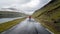 Unidentified man walking in the dramatic road landscape, Faroe Islands