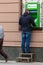 An unidentified man withdraws money from a street ATM using a stand.