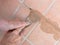 Unidentified man, workman, repairing grout between outdoor terracotta style patio tiles. Closeup detail.