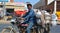 Unidentified men drive motorcycle with goods on a road