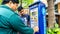 Unidentified men using the parking ticket payment machine at the side of the road