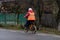An unidentified middle aged woman riding a bicycle on a cloudy dark day. Targoviste, Romania, 2019