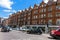 Unidentified people and traffic on typical English victorian Brompton road in a summer afternoon