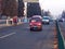 Unidentified people walking beside traffic in early morning smog.