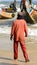 Unidentified Senegalese man in orange suit stands on the coast