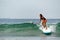 Unidentified surfer girl with a paddle rides on a surfboard on a wave in the Indian