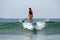 Unidentified surfer girl rolls on a surfboard on a wave in the Indian Ocean on a sunny