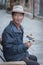 Unidentified Tibetan man in traditional clothes sit on a bench nearby Jokhang temple praying with prayer wheels