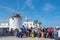Unidentified tourists waiting in line to ferry boat with a Traditional cycladic windmill at background on Paros island,