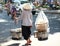 Unidentified woman carries bamboo yoke with foods for sale on the street of Saigon, Vietnam.