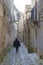 Unidentified woman walking away in ancient, typical narrow and cobblestone street in Erice, Sicily, Italy