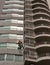 Unidentified worker use ropes outside the building cleaning the windows service on high-rise condominium building