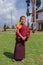 Unidentified young novice buddhist monk in traditional red robes standing in front of a monastery in Pelling, Sikkim, India
