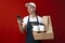 Uniform food delivery man holds a parcel and use a smartphone, online delivery concept