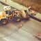 Uniform workers remove asphalt by folding it into an excavator bucket