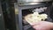 A uniformed chef puts dessert on metal tray into refrigerator to freeze