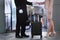 A uniformed doorman helps a woman into the hotel. A trolley with luggage. Business woman on a business trip. Holiday season.