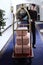 A uniformed doorman moves a cart with pink suitcases. A few suitcases on a luggage cart at the hotel. Doorman`s job.Concept of