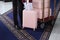 A uniformed doorman puts luggage from several suitcases on a luggage cart at the hotel. A white-gloved hand. A set of pink