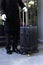 A uniformed doorman stands with a suitcase in his hand at the entrance to the hotel. The holiday season.The concept of hotel
