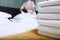 A uniformed maid changes bed linen in an expensive hotel room. The person is out of focus. Clean towels on the bed. The concept of