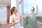 A uniformed maid controls a robot window cleaner. Clear window. Photos in the interior. The concept of cleaning and cleanliness.