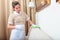 A uniformed maid is holding furniture cleaning spray. Cleaning of the hotel room. Copy of the space.