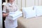 A uniformed maid holds white clean towels in her hands. Unrecognizable photo. The concept of the hotel business