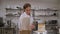 A uniformed pastry chef aligns the sides of the cake with a large metal spatula.