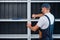 A uniformed worker is assembling a white metal shelving against a black clapboard wall