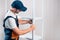 A uniformed worker is assembling a white metal shelving against a white clapboard wall