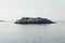 Uninhabited small isle with smooth granite rocks and green moss, lichen in blue Arctic Ocean in clear day, horizon, arctic.