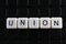 Union text word title caption label cover backdrop background. Alphabet letter toy blocks on black reflective background. White al