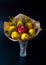 Unique festive bouquet of pomegranate, lemon and memoses on a black background. Fruit bouquet. Fruits and Vegetables of the