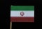 A unique flag of Iran on toothpick on black background. A horizontal tricolor of green, white and red with the national emblem in