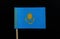 A unique flag of Kazakhstan on toothpick on black background. A gold sun with 32 rays above a soaring golden steppe eagle, both