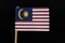 A unique flag of Malaysia on toothpick on black background. Consists of Fourteen horizontal stripes alternating red and white; in