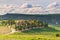 Unique green landscape in Orcia Valley, Tuscany, Italy. Dramatic sunset sky, dirt road and farm in cultivated hill range and