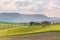 Unique green landscape in Orcia Valley, Tuscany, Italy. Morning light with mist and fog over cultivated hill range and cereal crop