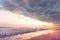 Unique salt lake with pink water and salt at sunset. Rows of wooden columns covered with salt crystals.