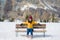 Unique Winter holidays trip to amazing snow valley - young happy and beautiful Asian woman sitting on bench alone enjoying snowy